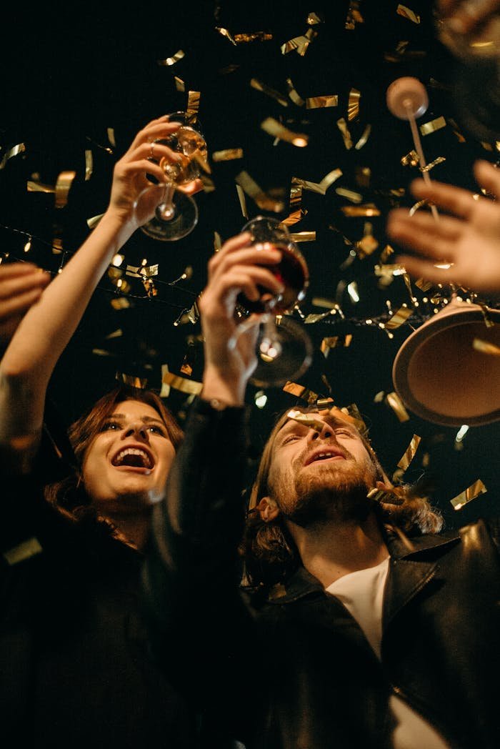 Group of friends enjoying New Years Eve party with confetti and drinks.